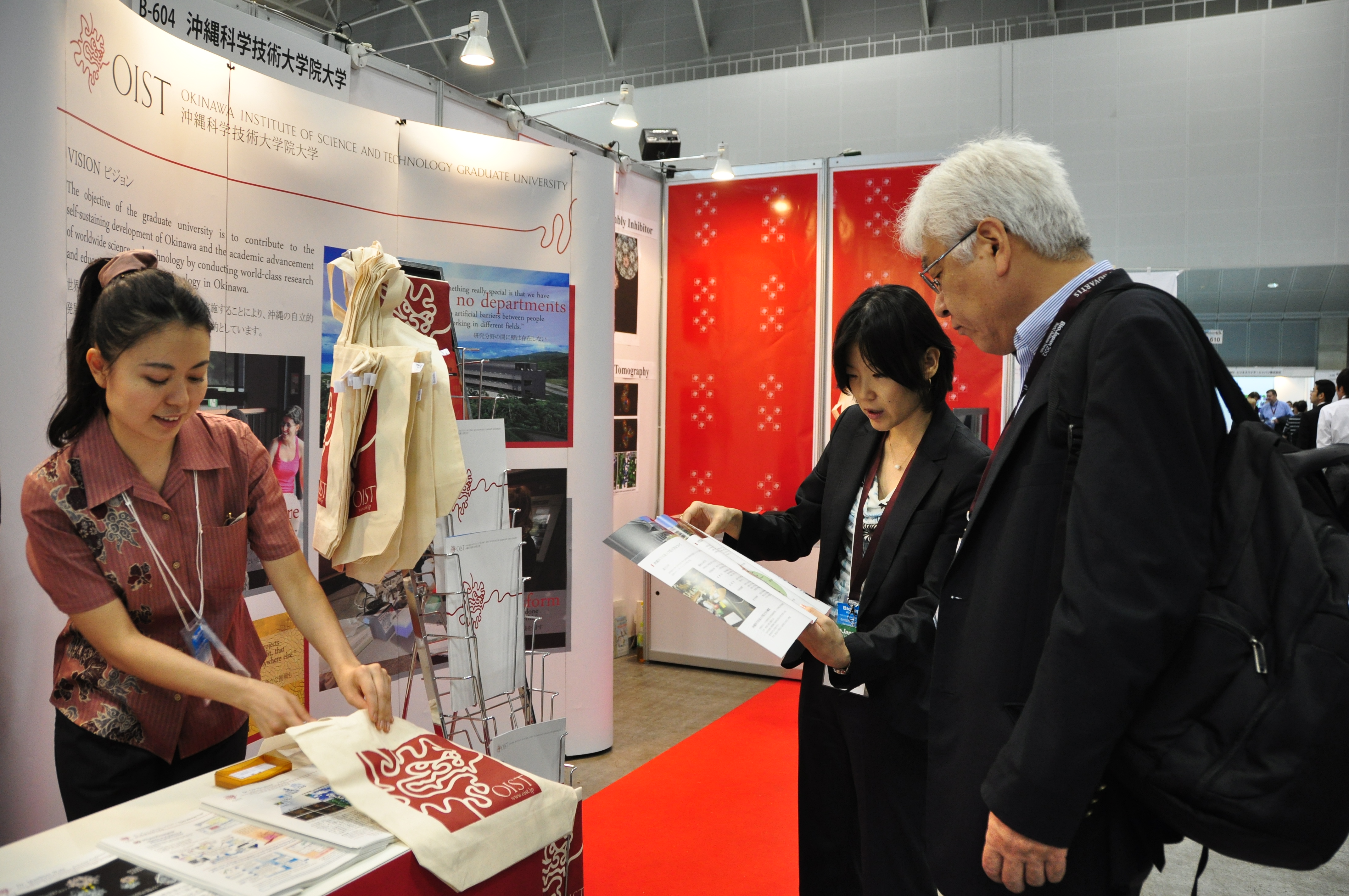 Ms. Nishimura (right) and Ms. Lee Nakasone attend a visitor to the OIST booth