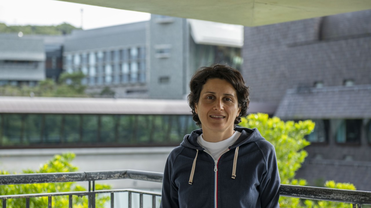 Matin Miryeganeh on the OIST campus with out-of-focus lab buildings behind her