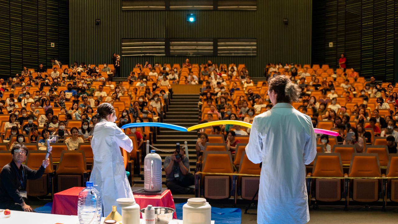 Two scientist in white coat on the stage and audience