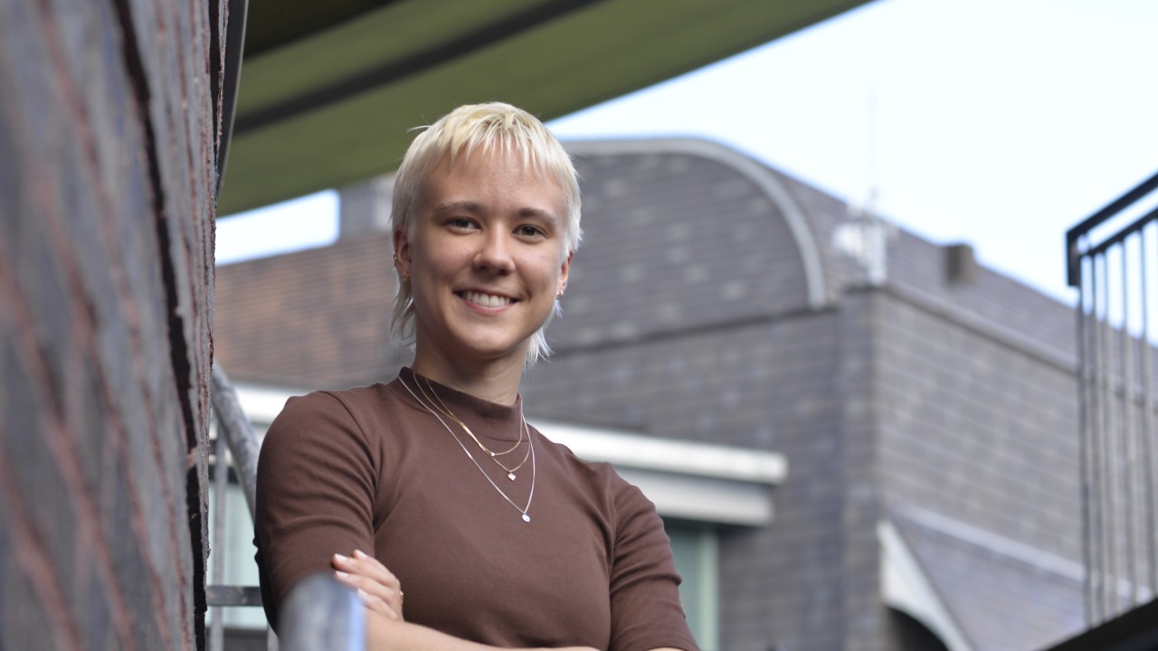 Woman standing with arms crossed on outdoors stairs looking down at camera