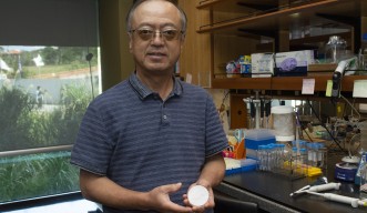 Professor Ichiro Maruyama holds up a petri dish of C. elegans worms.
