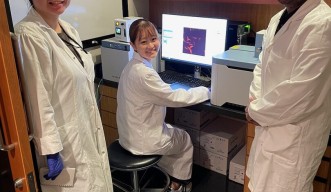 Student from Keio University with lab members in white coat