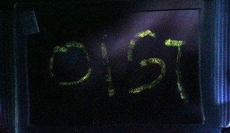 The letters OIST are spelled out in glowing lights thanks to mechanoluminescence from amorphous thin films. This is a photo taken with long exposure.