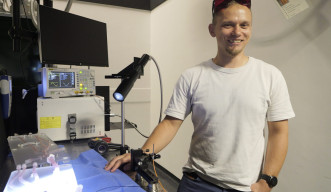 A person smiling beside a desk