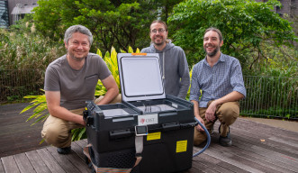 A photo of Peter Babiak, John Parker, and Zdenek Lajbner behind the newly developed cephalopod egg incubator, a large black box with wheels. 