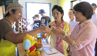 Minister Aiko Shimajiri and lawmaker Natsumi Higa tasting local honey