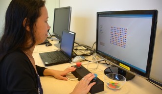 実験で使用したゲームを実演する発達神経生物学ユニットの古川絵美博士。