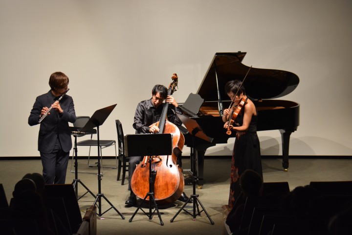 flutist, bass player and violinist playing on the stage