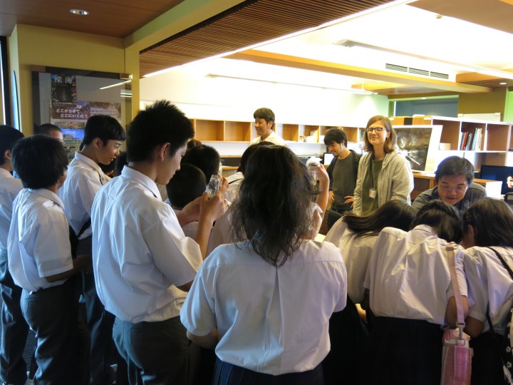 Junior hight school students gathered around scientists 