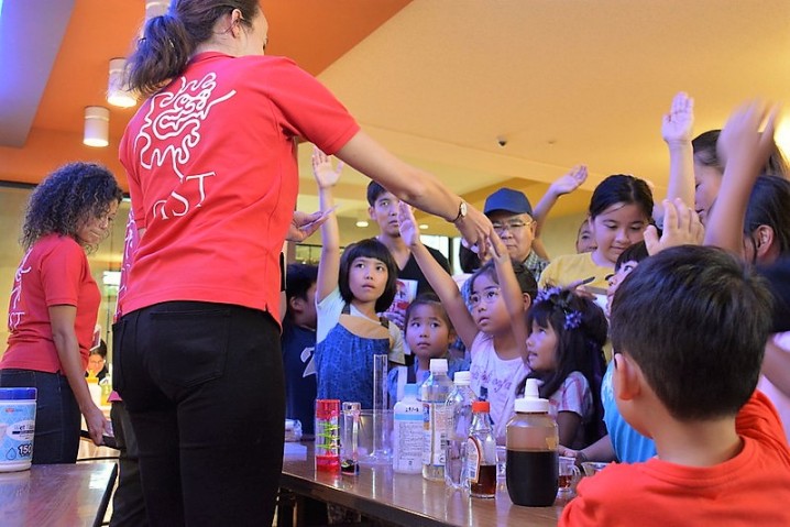 Children gathering around 2 scientists
