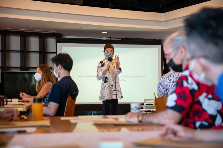 Dr. Takayama gesturing as she explains with the screen behind her.