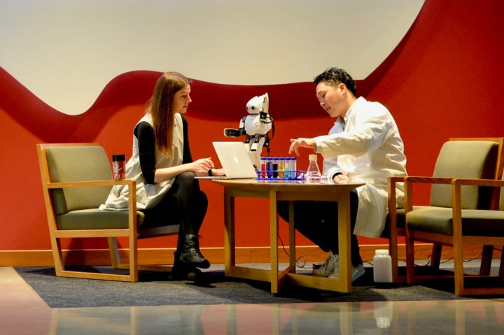 2 people talking over tha table with a small robot