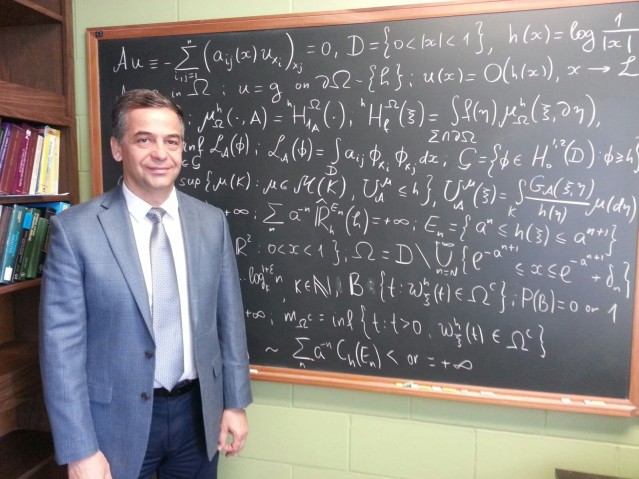 Professor Abdulla in front of blackboard filled with symbols