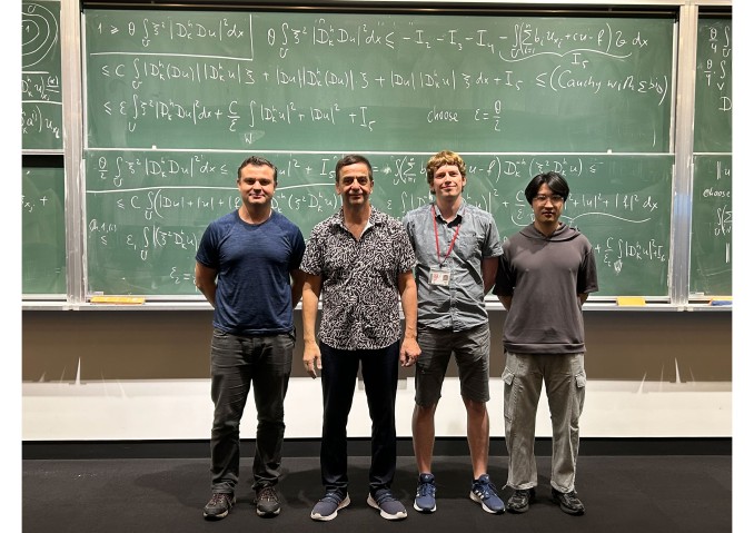 Four group members in front of a blackboard