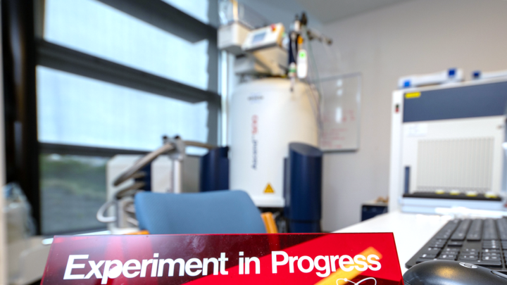 a sign saying Experiment in Progress on a desk and a machine on the background