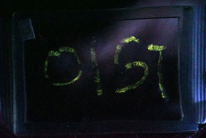 The letters OIST are spelled out in glowing lights thanks to mechanoluminescence from amorphous thin films. This is a photo taken with long exposure.