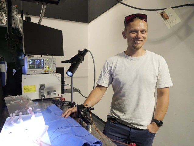 A person smiling beside a desk
