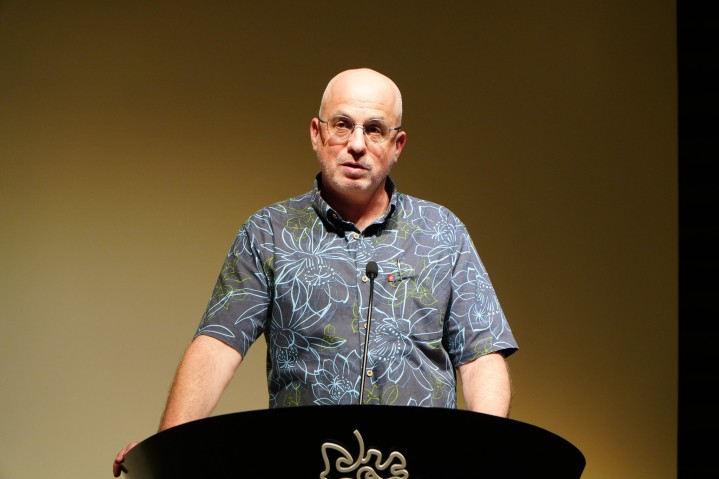 OIST Executive Vice President Gil Granot-Mayer speaking at a podium bearing the OIST logo 