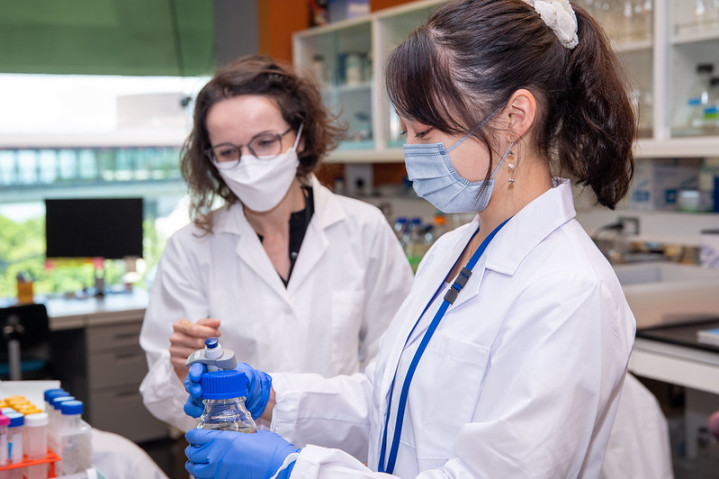 Two researchers in white coat working in a lab