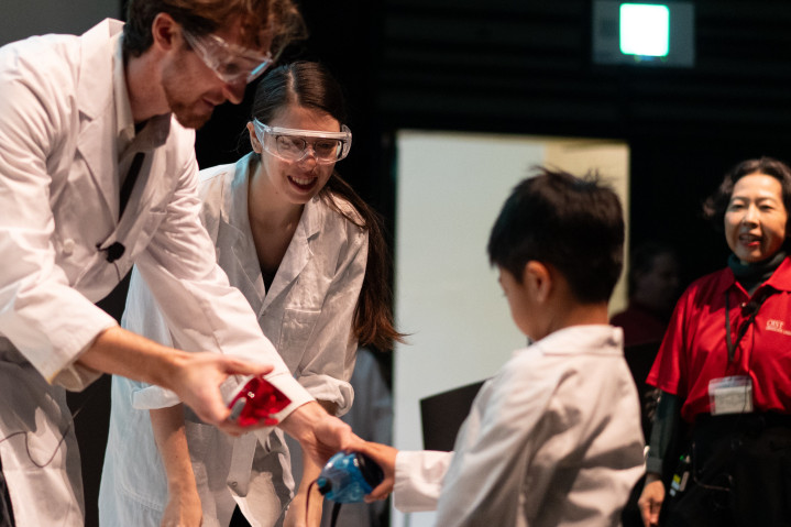 Jack handing colored glasses to a child participant of the Science Show.
