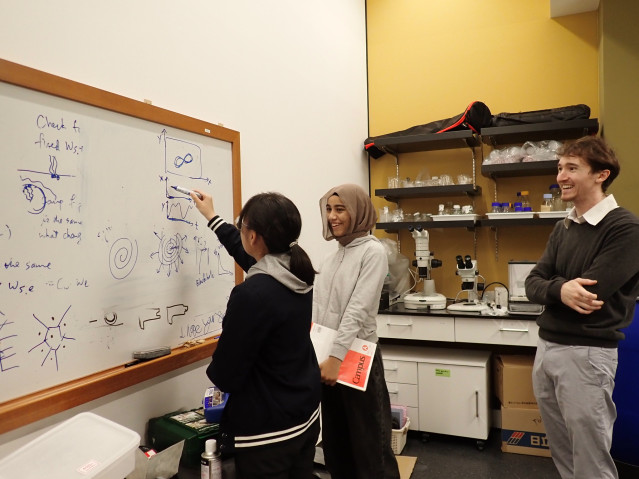 Jack talking to students writing on a whiteboard.