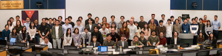 Participants from OIST and Keio University pose together for a group photo at the OIST-Keio Showcase Talk Series Vol. 10, standing at the front of a seminar room.