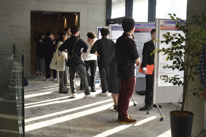 Attendees discuss research findings during the poster session at OIST Land nexus, held on the second day of the event.