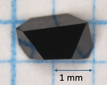 A close-up photograph of a black spinel crystal.