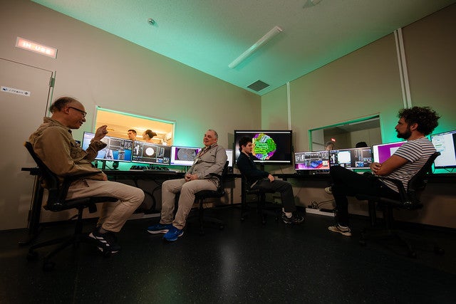 Four people sitting in front of desks and discussing