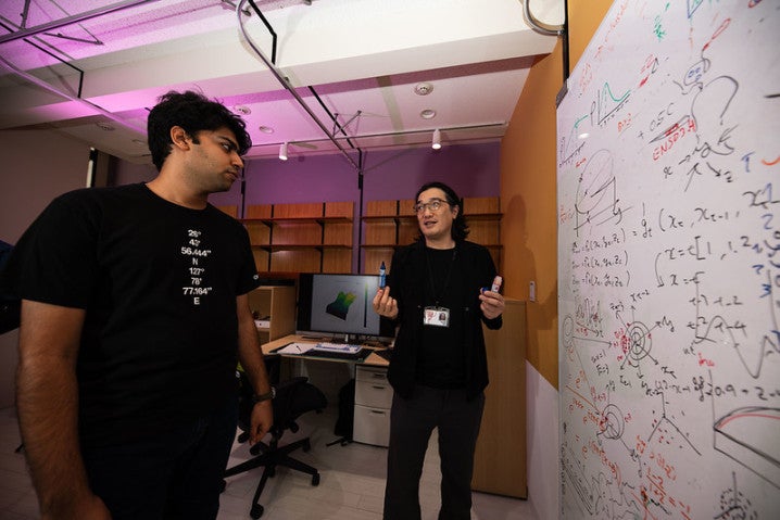 Two person talking in front of a white board