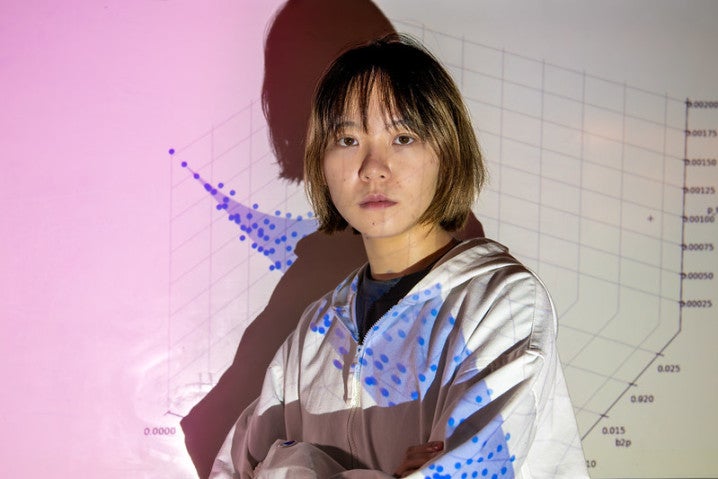 A researcher stands in front of a wall with a graph projected onto it