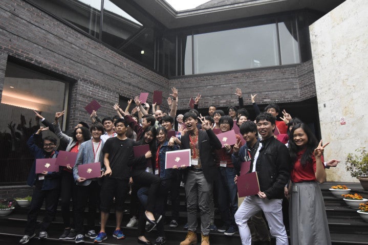 a group of people standing on the steps holding red folders