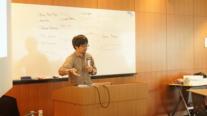 a person talking in front of a white board