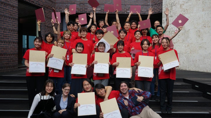 a group of students in red shirts holding certificates
