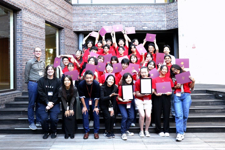 a group of students in red shirts holding certificate and people in black sirts 