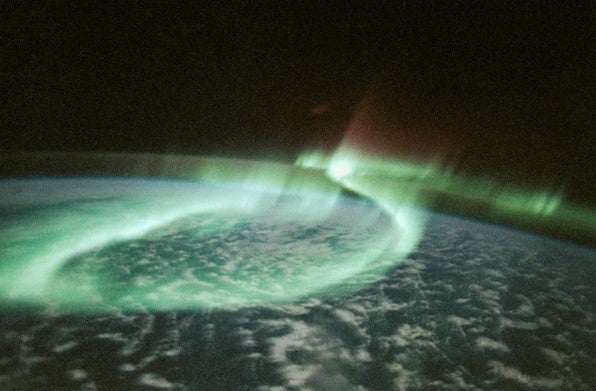 Bright green lights, photographed over the Earth's atmosphere by a crew member on the Space Shuttle Discovery.