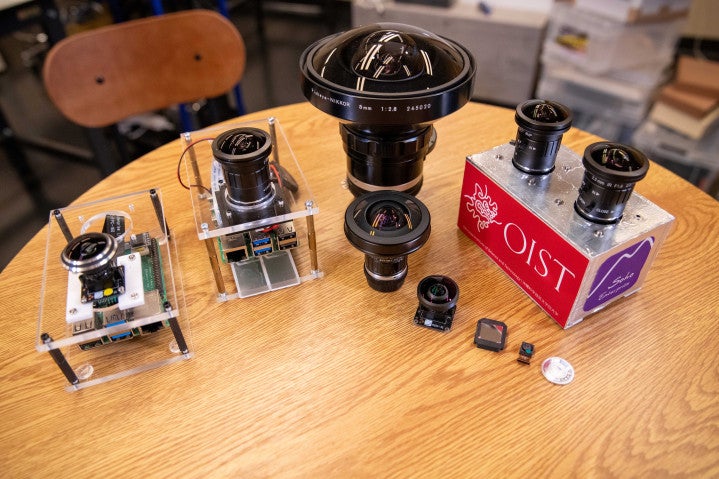 A range of cameras sit on a table, varying in size.