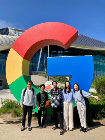 Group photo in front of the large, colorful Google logo in front of the Google Visitor Experience. The five people are all smiling in the sun.