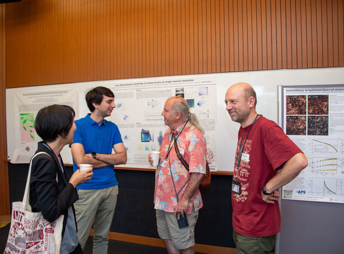 Four researchers discussing in front of research posters