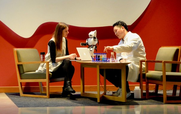 2 people talking over tha table with a small robot