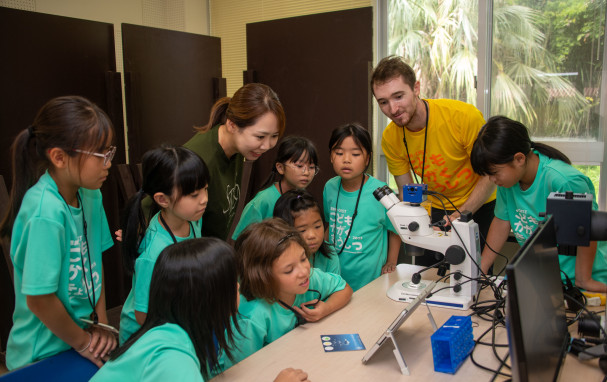 Jack working with students at a microscope.