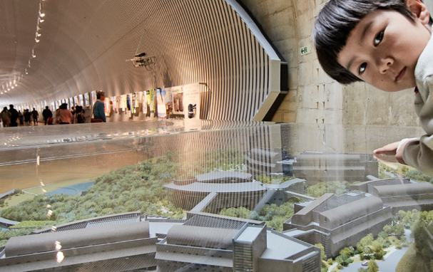 A child pausing beside the scale model of OIST campus buildings