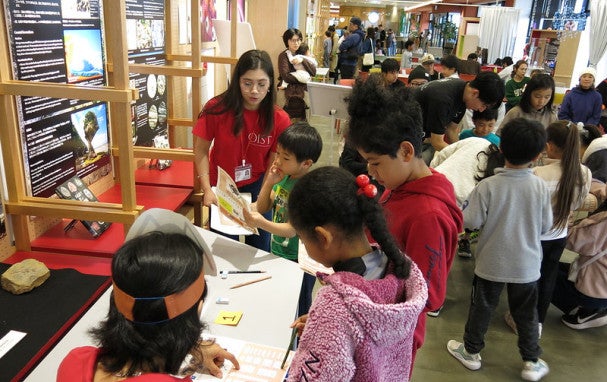 Children gathering around a sheet spread on a table