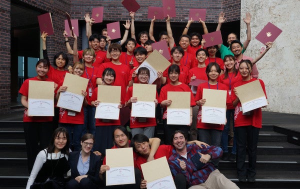 a group of students in red shirts holding certificates