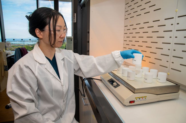 A researcher in a white coat holding laboratory equipment