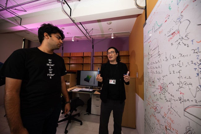 Two person talking in front of a white board