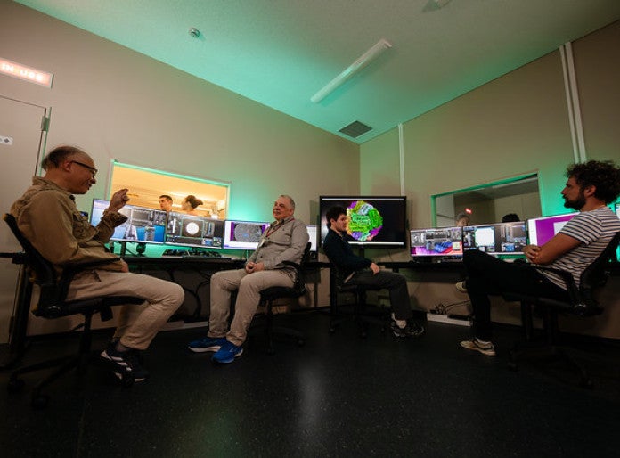 Four people sitting in front of desks and discussing