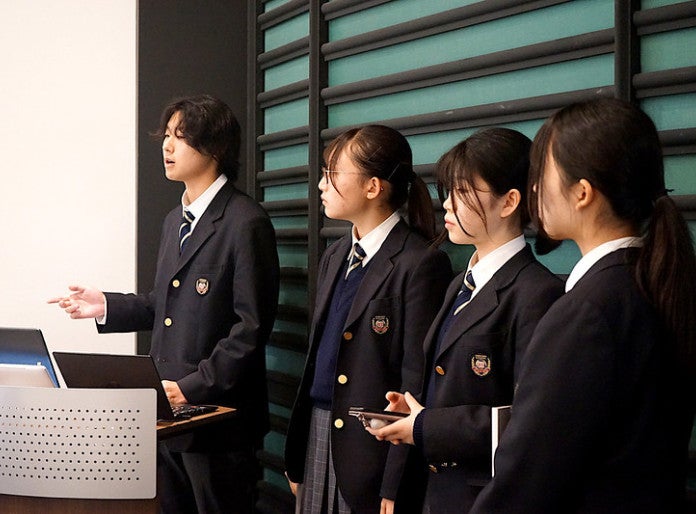 students in school uniform giving presentation
