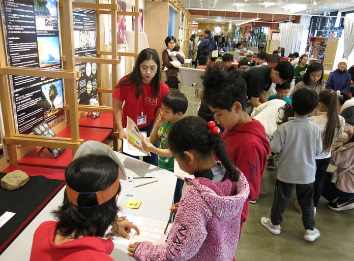 Children gathering around a sheet spread on a table